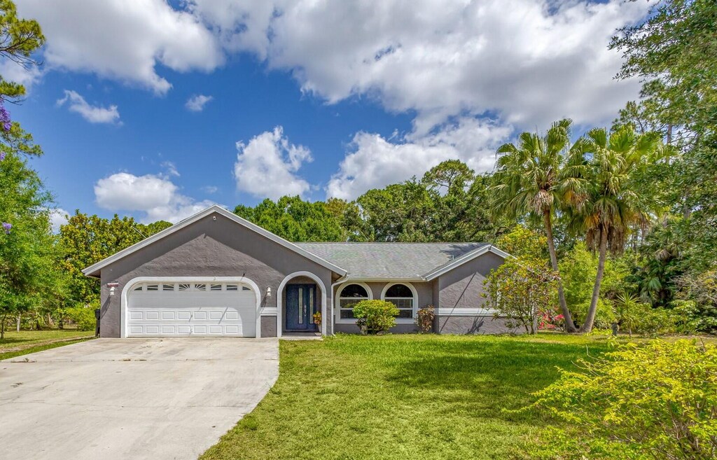16823 Valencia Blvd, Loxahatchee, FL 33470 - ranch-style home with an attached garage, driveway, a front yard, and stucco siding