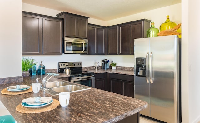 12134 SW Rimini Way, Port Saint Lucie, FL 34987 - kitchen with a sink, appliances with stainless steel finishes, dark stone counters, and dark brown cabinets