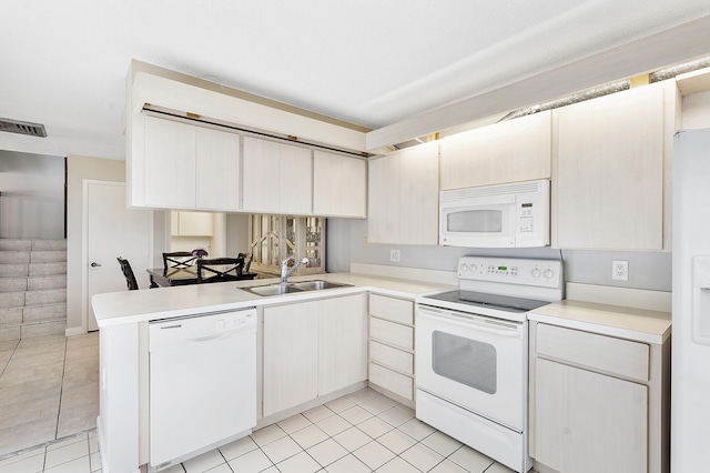 kitchen with a sink, white appliances, light countertops, a peninsula, and light tile patterned floors