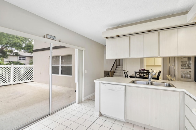 kitchen with a peninsula, light tile patterned flooring, light countertops, a sink, and dishwasher