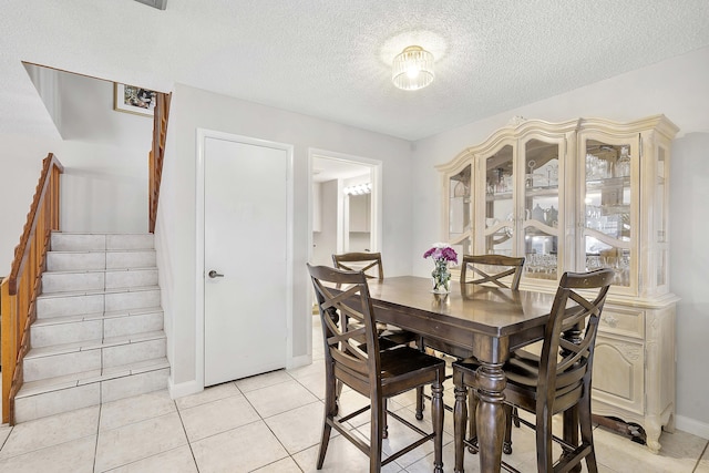 dining space with baseboards, light tile patterned flooring, stairs, and a textured ceiling