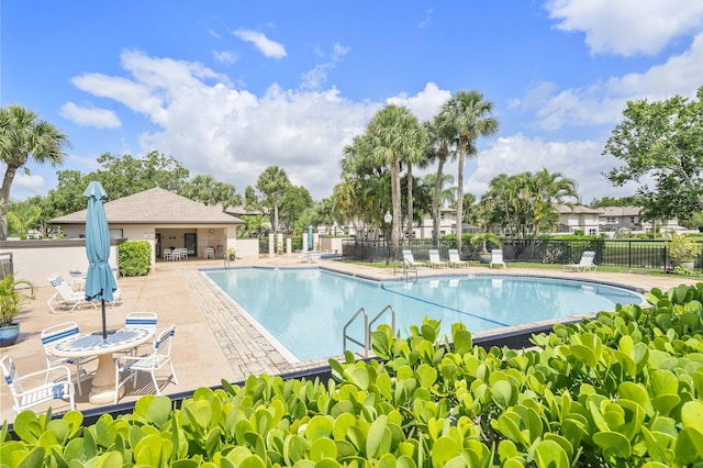 community pool with a patio and fence