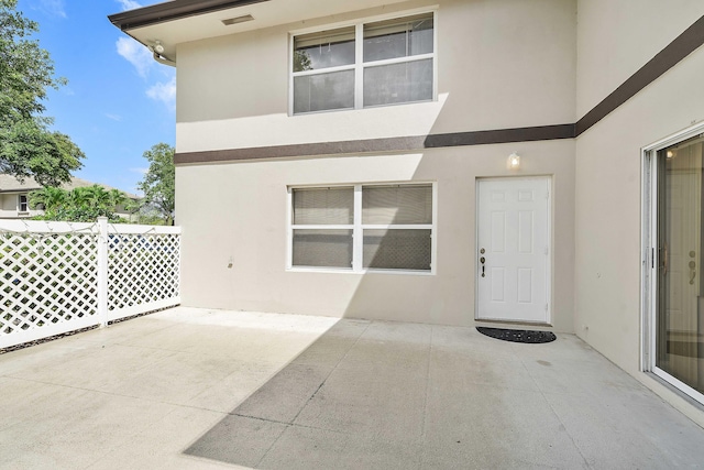 property entrance with a patio and stucco siding