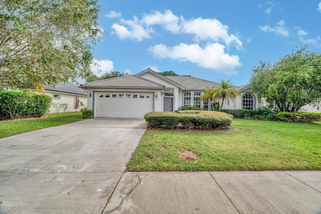 ranch-style house featuring a garage, a front lawn, stucco siding, a tiled roof, and concrete driveway