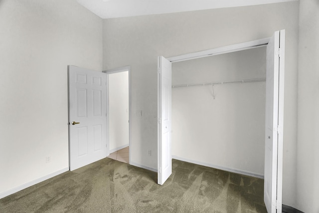 unfurnished bedroom with a closet, carpet, and baseboards