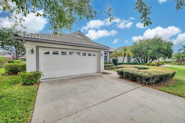 view of front of house with a tiled roof, driveway, a front yard, an attached garage, and stucco siding