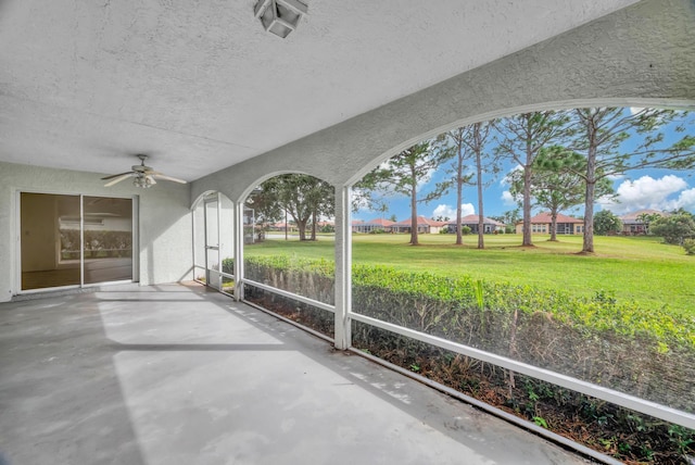 unfurnished sunroom with ceiling fan and a residential view