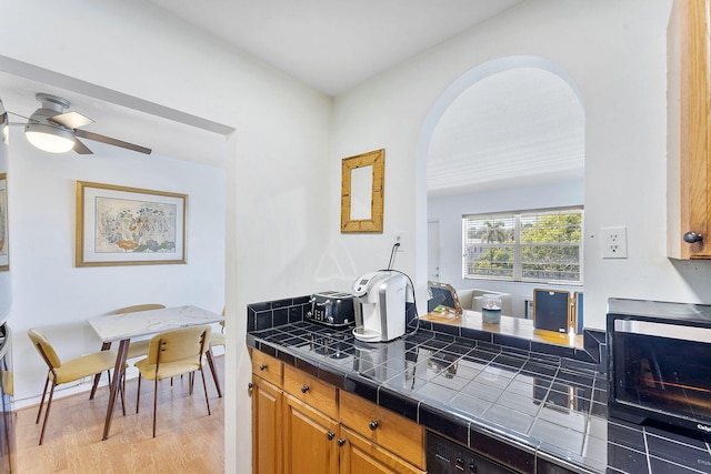 2520 S Federal Hwy Unit 14, Boynton Beach, FL 33435 - kitchen featuring a ceiling fan, arched walkways, a toaster, light wood-style floors, and tile counters