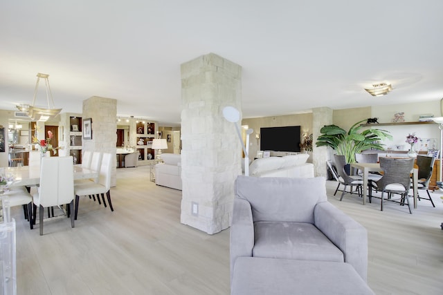 living area featuring decorative columns and light wood-style flooring