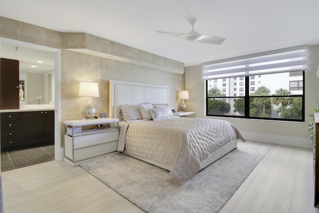 bedroom featuring light wood-style floors, a sink, ensuite bathroom, and ceiling fan