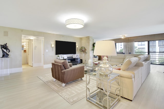 living area with baseboards, light wood-type flooring, and visible vents