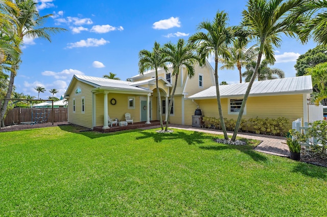 view of front of house featuring a porch, fence, metal roof, and a front lawn