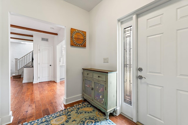 foyer with stairs, baseboards, visible vents, and hardwood / wood-style flooring
