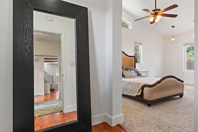 bedroom with baseboards, wood finished floors, and high vaulted ceiling