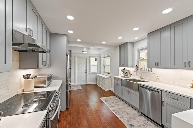 kitchen featuring a sink, appliances with stainless steel finishes, gray cabinetry, and under cabinet range hood