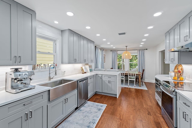 kitchen featuring recessed lighting, under cabinet range hood, a sink, appliances with stainless steel finishes, and gray cabinetry