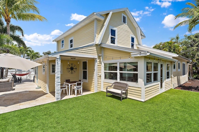 back of house with outdoor dining area, a patio area, and a yard