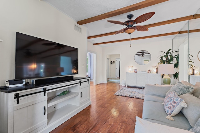 living room featuring wood finished floors, a ceiling fan, beam ceiling, and visible vents