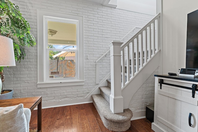 stairway featuring brick wall and wood finished floors