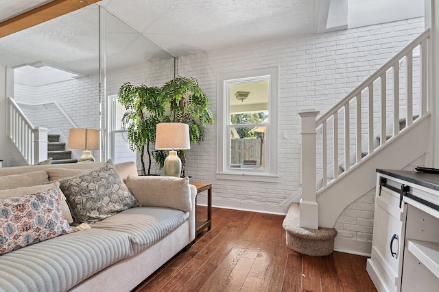 living area with brick wall, baseboards, stairs, and a textured ceiling