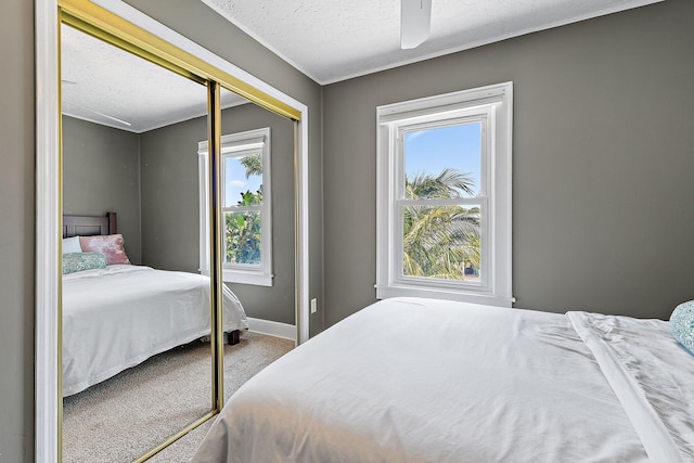 carpeted bedroom featuring baseboards, multiple windows, ceiling fan, and a closet