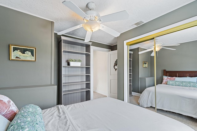 carpeted bedroom featuring ceiling fan, a textured ceiling, visible vents, baseboards, and a closet