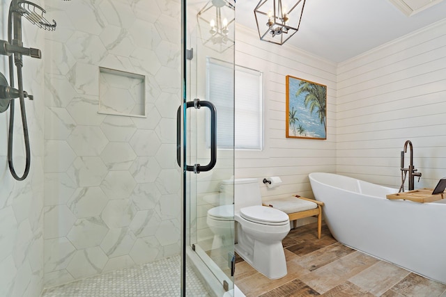 bathroom featuring crown molding, toilet, a freestanding tub, wood finished floors, and a stall shower