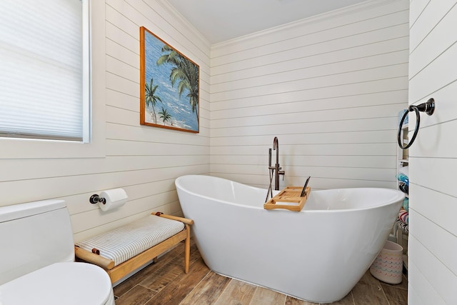 bathroom featuring ornamental molding, wood finished floors, wooden walls, and toilet