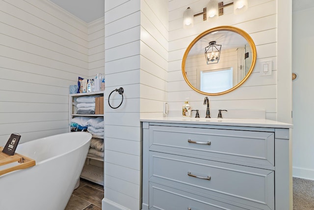 full bath featuring wooden walls, vanity, and a freestanding bath
