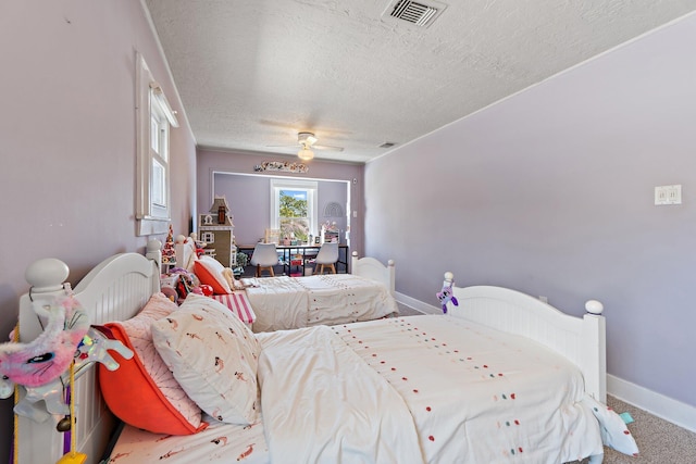carpeted bedroom with visible vents, a textured ceiling, baseboards, and ceiling fan
