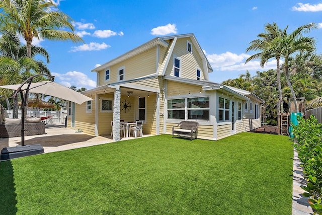 back of property with fence, a lawn, and a patio area
