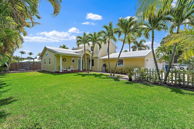 rear view of property featuring fence, a yard, and metal roof