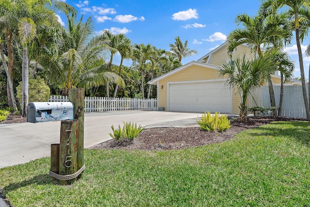 view of side of property with fence, an attached garage, a lawn, and driveway