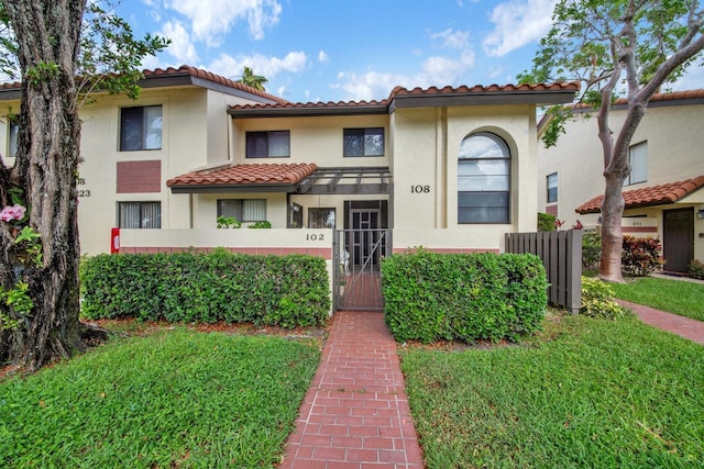view of front of property featuring fence, a gate, a tiled roof, and stucco siding