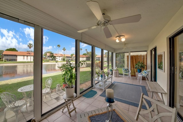 sunroom featuring a water view, a ceiling fan, and a residential view