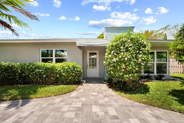 doorway to property featuring stucco siding, a chimney, and fence