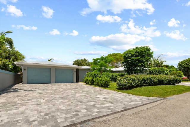 view of front facade featuring decorative driveway, stucco siding, a front lawn, and an attached garage
