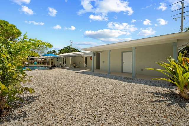 back of house with a patio area, an outdoor pool, and stucco siding