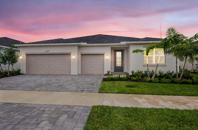 view of front facade featuring stucco siding, an attached garage, decorative driveway, and a front yard