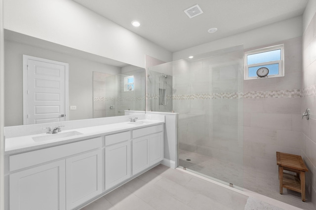 bathroom with a sink, a walk in shower, and visible vents