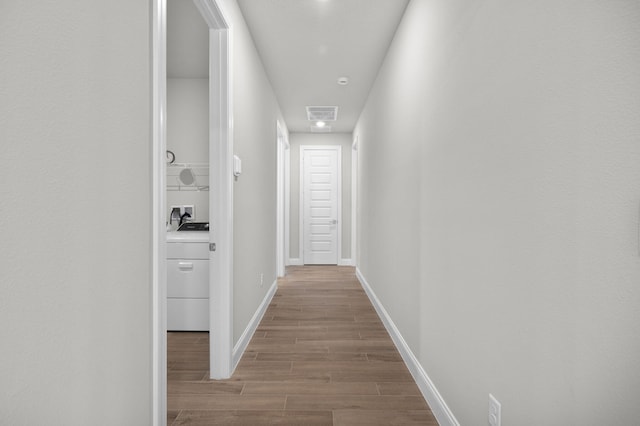 corridor featuring baseboards, visible vents, washer / clothes dryer, and wood finished floors