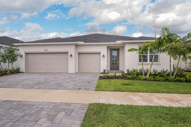 view of front of home with decorative driveway, an attached garage, a front lawn, and stucco siding