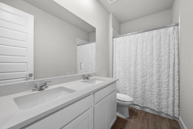 full bath with double vanity, a sink, wood finished floors, and toilet