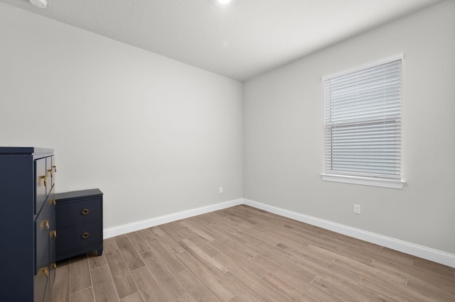 unfurnished room with baseboards and light wood-style floors