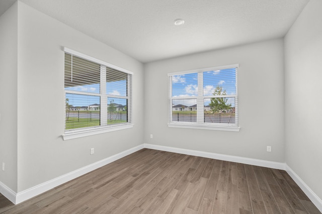 spare room featuring plenty of natural light, baseboards, and wood finished floors