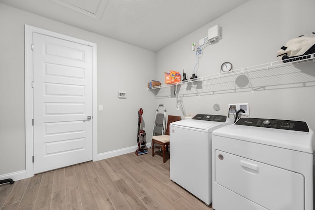 laundry room featuring laundry area, baseboards, washer and dryer, and light wood-type flooring