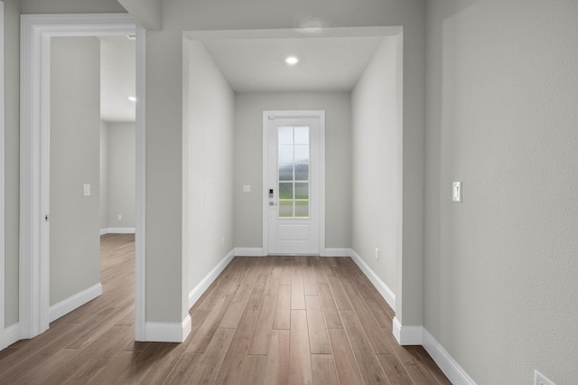 doorway with baseboards and wood finished floors