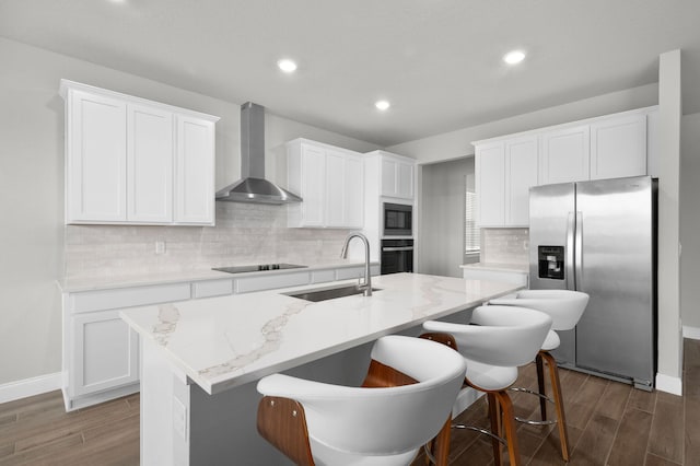 kitchen featuring wall chimney range hood, black appliances, a sink, and dark wood-type flooring