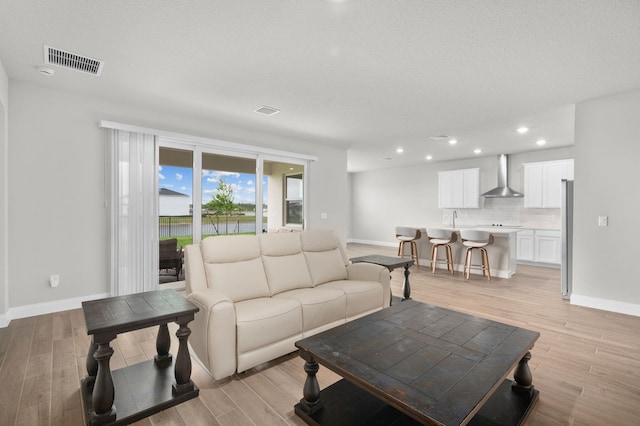 living area with visible vents, recessed lighting, light wood finished floors, and baseboards