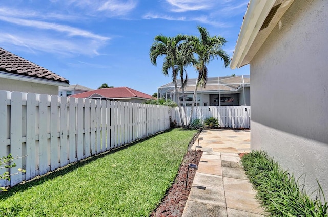 view of yard featuring a fenced backyard, glass enclosure, and a patio